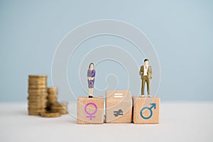 Gender pay equality concept. Miniature of man , woman on wooden cube block and flipped unequal to equal sign with blurred stack