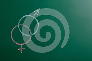 Gender symbols drawn on green chalkboard. Sex education