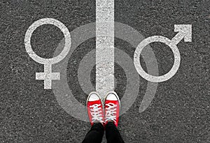 Gender symbols of love on asphalt background. Selfie feet and red sneaker shoes with male and female white sign on road.