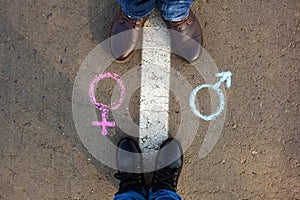 Gender symbols or signs for male and female drawn on asphalt. Male and female legs