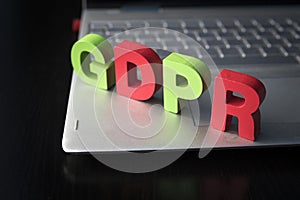 General Data Protection Regulation - GDPR wooden letters set on the bottom of laptop at black background. Data Protection Concept