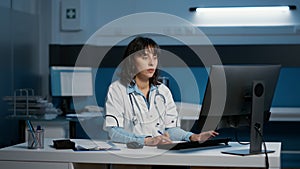 General practitioner analyzing patient expertise typing medical report on computer