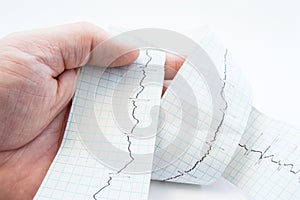 General practitioner, cardiologist or paramedic holding in hand tape with recorded electrocardiogram EKG, ECG wave. Diagnostic p