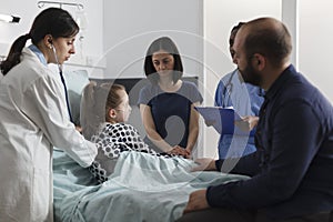 General practitioner consulting ill little girl under treatment inside clinic pediatric ward
