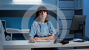 General practitioner nurse sitting at desk working over hours at patient diagnosis report