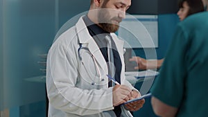 General practitioner taking notes at consultation with old patient