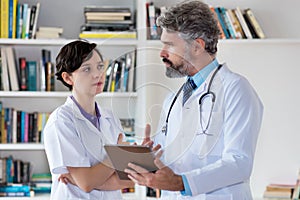 General practitioner talking with nurse about therapy of patient