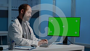 General practitioner typing medical expertise on computer with greenscreen chroma key template