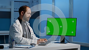 General practitioner typing medical expertise on computer with greenscreen chroma key template