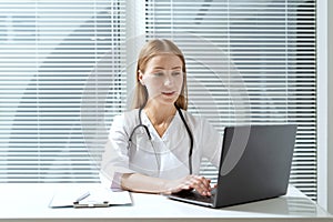 General practitioner working on laptop in clinic