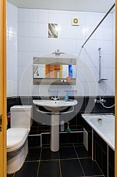 General view of a classic bathroom interior in an apartment, with black and white tiles