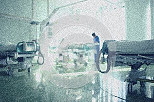 General view of intensive care unit. Doctor stands near the patient bed surrounded by equipment. Grained background