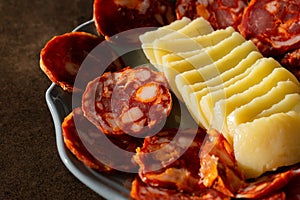 A traditional Alentejo sausage, known as paio, sliced and displayed alongside a rustic cheese wheel on a white plate. photo