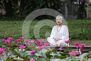 Elderly Woman Meditating by Pond Surrounded