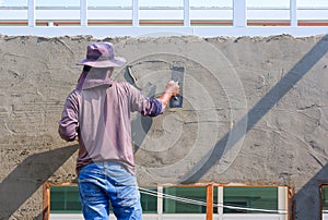 Builder worker using trowel to plastering cement on the wall inside of house construction site