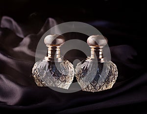 Two perfume perfume bottles on black silk background.