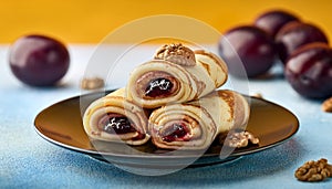 Rolled pancakes with plums jam and walnuts filling on a bright background