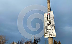 Red Light Camera Traffic Sign with Bilingual Text on a Street Pole