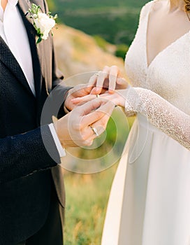The groom places the wedding ring on the bride s finger