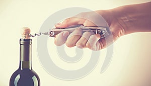 Opening a wine bottle with corkscrew, isolated on white