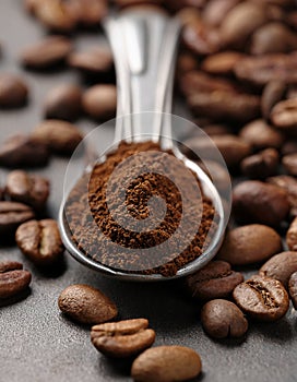 Spoon with coffee grounds and roasted beans on table, closeup