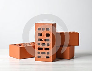 Three red bricks on textured table against light background. Building material