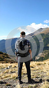 Tourist with backpack in mountains, back view