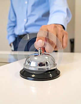 Man ringing hotel service bell at light table