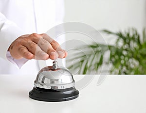 Man ringing hotel service bell at light table
