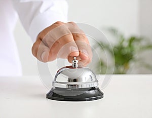 Man ringing hotel service bell at light table