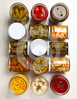 Different pickled products in jars on table, top view