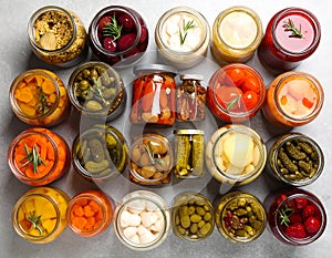 Different pickled products in jars on table, top view