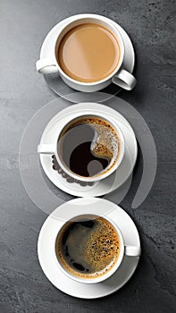 Cups with different types of coffee on dark grey table, flat lay