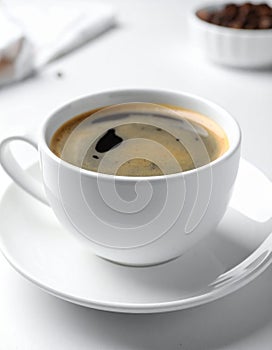 Cup of aromatic coffee on white table, closeup.