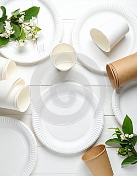 Set of disposable tableware on white wooden table