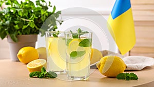 Mint lemon juice, fresh leaves and fruits on a light brown table, flat flag