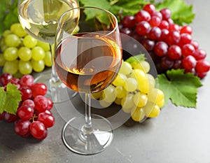 Fresh ripe grapes and a glass of wine on a gray table, close up.