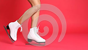 Woman in elegant white ice skates on red background, closeup of legs. Space for text