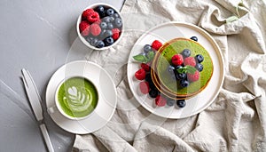 Flat lay pancakes topped with berries and green matcha latte