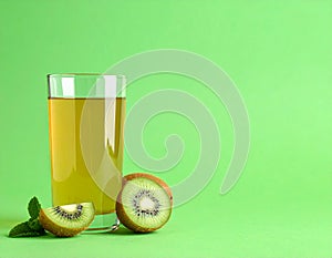 Glass of refreshing drink and cut kiwi on green background, space for text