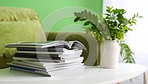 Stack of Magazines on White Table with Green Plant Decor