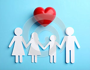 Paper family figures and red heart on light blue background, flat lay. Insurance