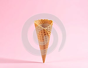 Empty wafer ice cream cone on pale pink background