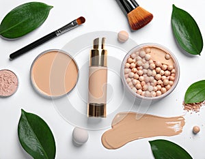 Assorted makeup products on a white surface include a liquid foundation bottle with a gold cap