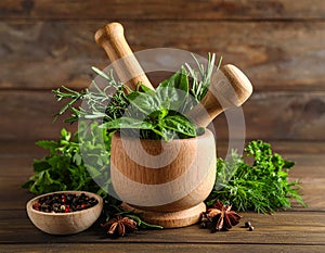 Different aromatic herbs, mortar with pestle and spices on wooden table, closeup