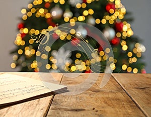 Music notes and table near Christmas tree on blurred background, bokeh effect. Banner