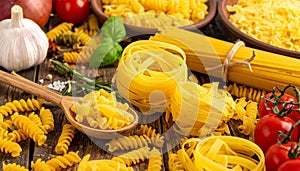 Raw pasta of different types on a wooden table, products and spices, close-up.