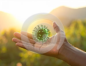 Human hand holding green virus model with sunlight and nature background