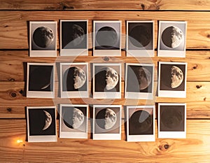 Collection of moon phase photos on rustic wooden table under warm light