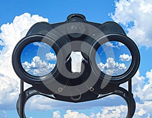 Binoculars with blue sky and clouds reflected in the lenses - future vision metaphor